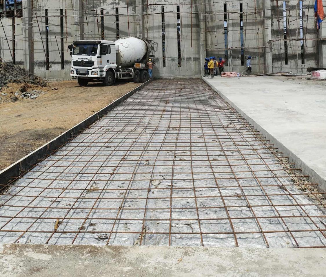 Reinforcement mesh over vapour barrier ready for the slab pour of a 10,000-tonne copra warehouse, with a concrete mixer truck on site